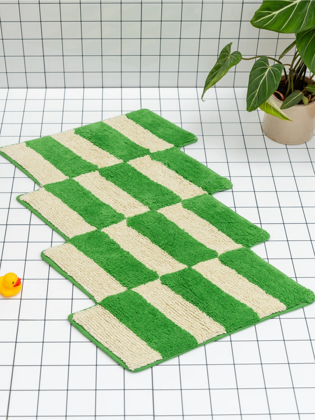 TARTA GELATINA Cassette Bath Mat, a playful retro-inspired bath mat crafted from plush tufted cotton, featuring a bold checkerboard pattern in vibrant green and soft cream. Its shaggy texture and graphic design offer a touch of contemporary style and comfort. Ideal for adding a bright pop of color to modern bathrooms, guest baths, or eclectic interior spaces.