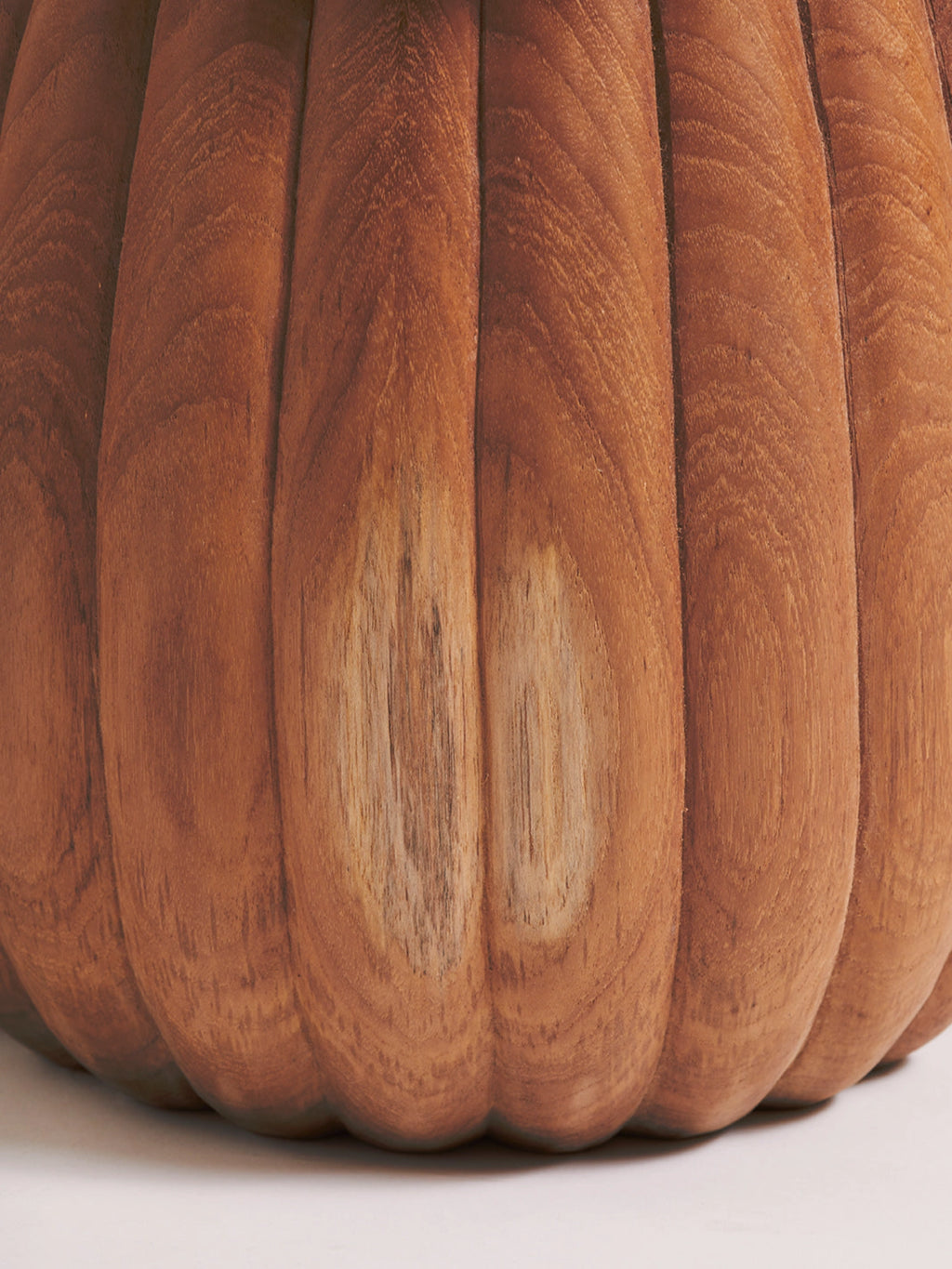 Heaps & Woods Charlotte Stool, a warm brown solid teak wood stool featuring a distinctive fluted, ribbed design and a rounded, organic silhouette. The natural wood grain and varying tones, including lighter blonde patches, add to its rustic charm and unique character. Perfect as an organic modern accent stool, bedside table, or contemporary side table in living rooms and bedrooms.