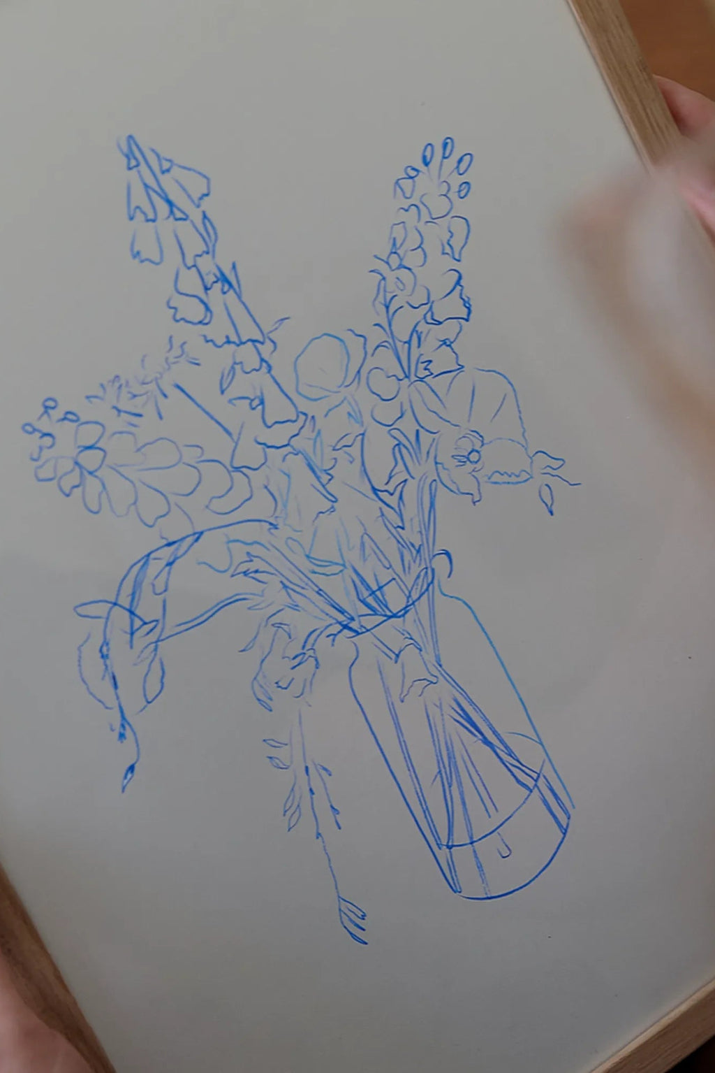 The Poster Club Flower Study, a minimalist abstract floral line art print featuring a vibrant blue sketch of various flowers and foliage arranged in a vase, set against a soft off-white background. This contemporary botanical illustration is presented in a natural light oak frame, capturing an organic, hand-drawn aesthetic. Perfect as modern wall art for Scandinavian living rooms, minimalist bedrooms, or a stylish addition to a gallery wall.