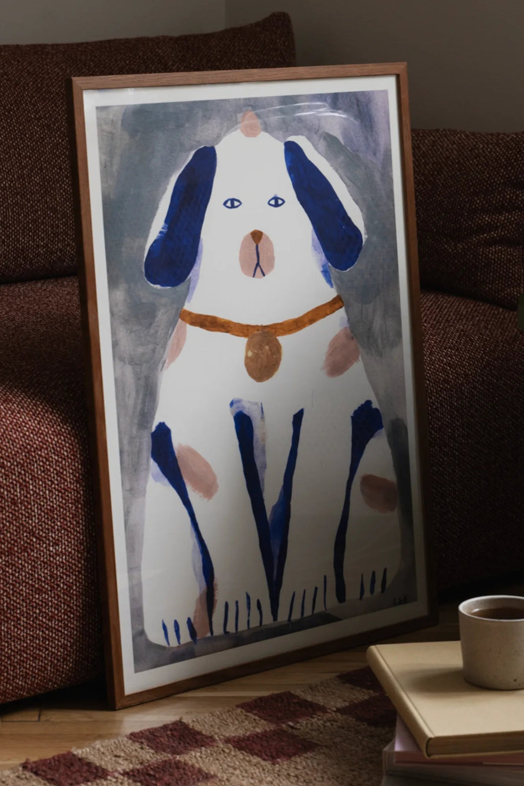 The Poster Club Guardian Dog, an abstract art print featuring a charming white dog with deep blue ears and brushstroke spots, a light pink nose, and a brown collar with a gold tag, set against a soft grey-blue background, all within a natural wood frame. This playful and modern minimalist dog poster is perfect for adding whimsical wall art to a contemporary living room, children's bedroom, or nursery decor.