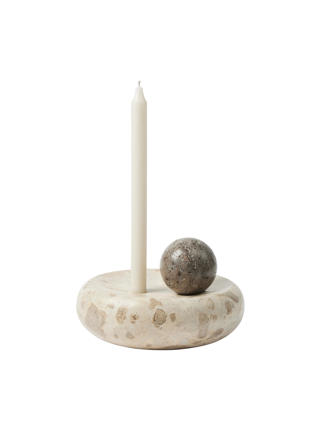 Kristina Dam Coherent Candle Sculpture, an organic modern candle holder crafted from natural travertine stone with a rounded, sculptural base in light beige and cream tones. It features a dark, textured stone sphere and a single off-white taper candle, embodying a minimalist and brutalist aesthetic. This unique decorative object is perfect for contemporary shelf styling, dining table centerpieces, or adding a sophisticated touch to Scandinavian living rooms and entryways.