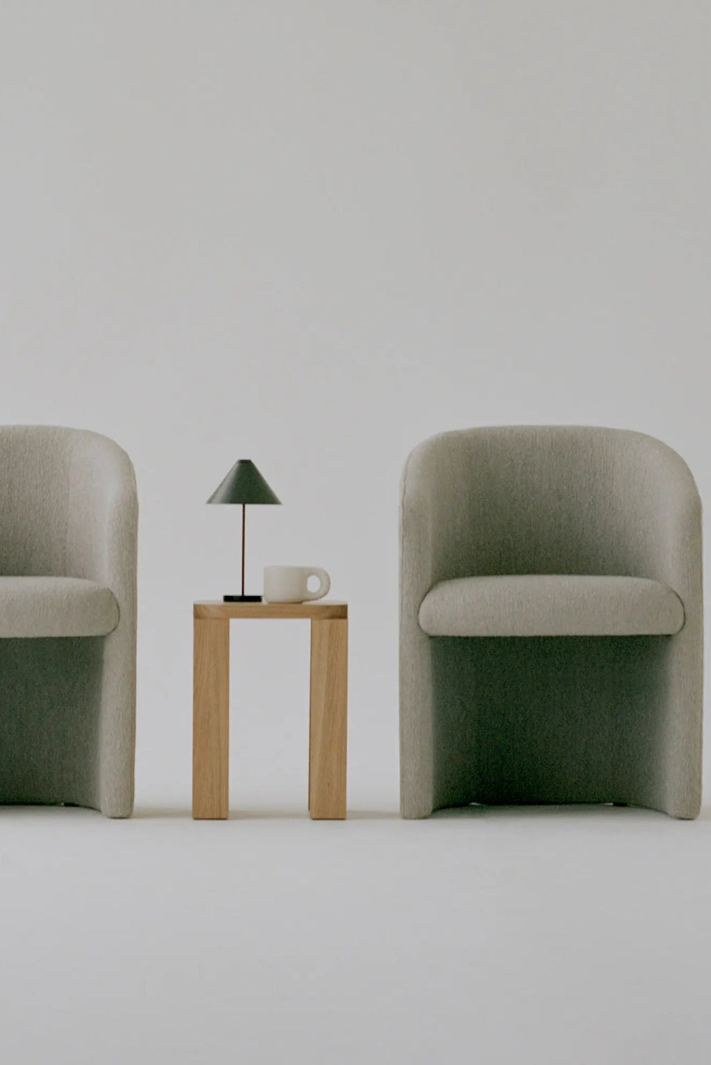 New Works Covent Club Chair, a light greige upholstered lounge chair featuring a soft, textured bouclé fabric and a distinctive curvilinear, sculptural form with a deep, inviting seat. This contemporary club chair is ideal for minimalist living rooms, organic modern spaces, or Scandinavian-inspired lounge areas.