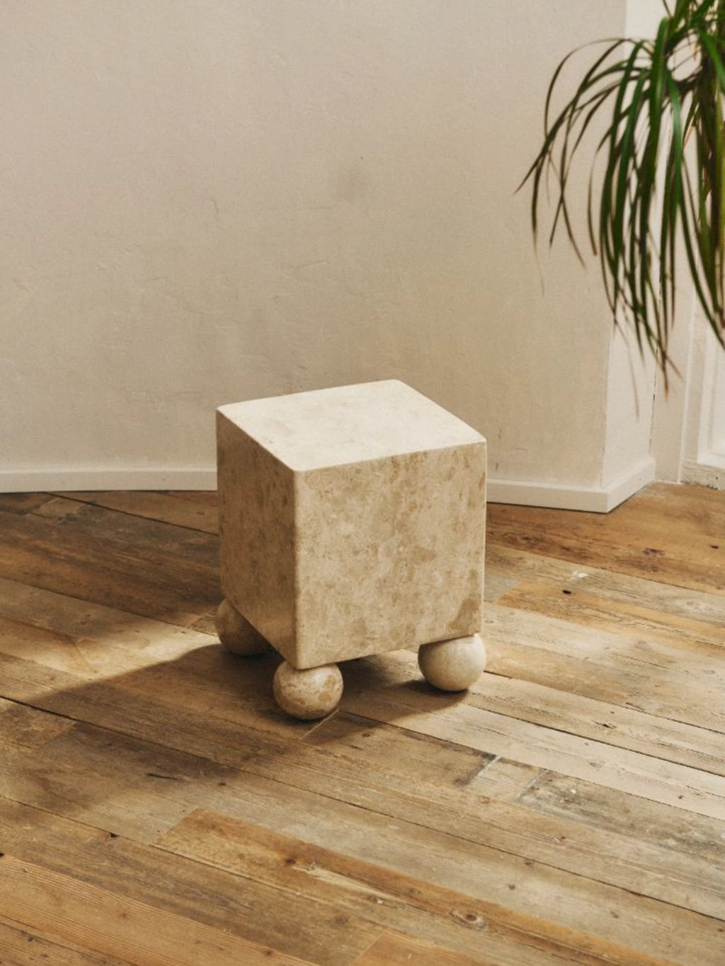 Heaps & Woods Aurelia Side Table, a unique cube-shaped side table crafted from natural cream-colored travertine stone with a textured, porous finish and distinct spherical ball legs. This organic modern accent table offers a minimalist brutalist-inspired aesthetic, perfect as a sculptural living room side table or a statement bedside table for contemporary interiors.