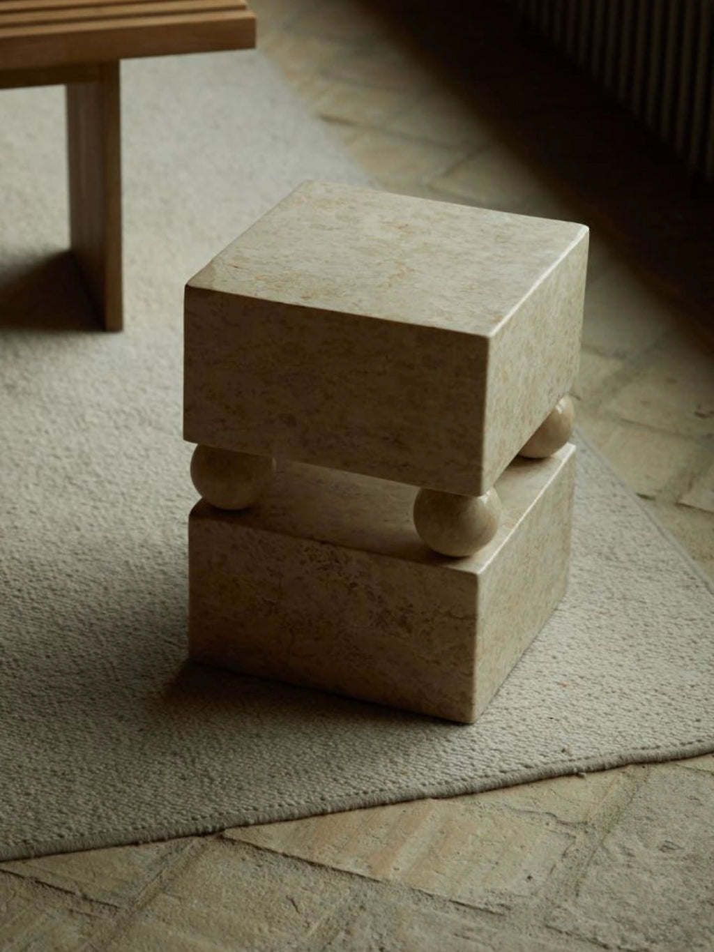Heaps & Woods Conor Side Table, a striking brutalist-inspired side table crafted from natural beige travertine stone, featuring two stacked rectangular blocks separated by rounded spherical supports. This sculptural, minimalist design highlights the porous texture and warm tones of the solid stone, creating a unique visual interest. Perfect as an organic modern living room accent or a contemporary bedside table.