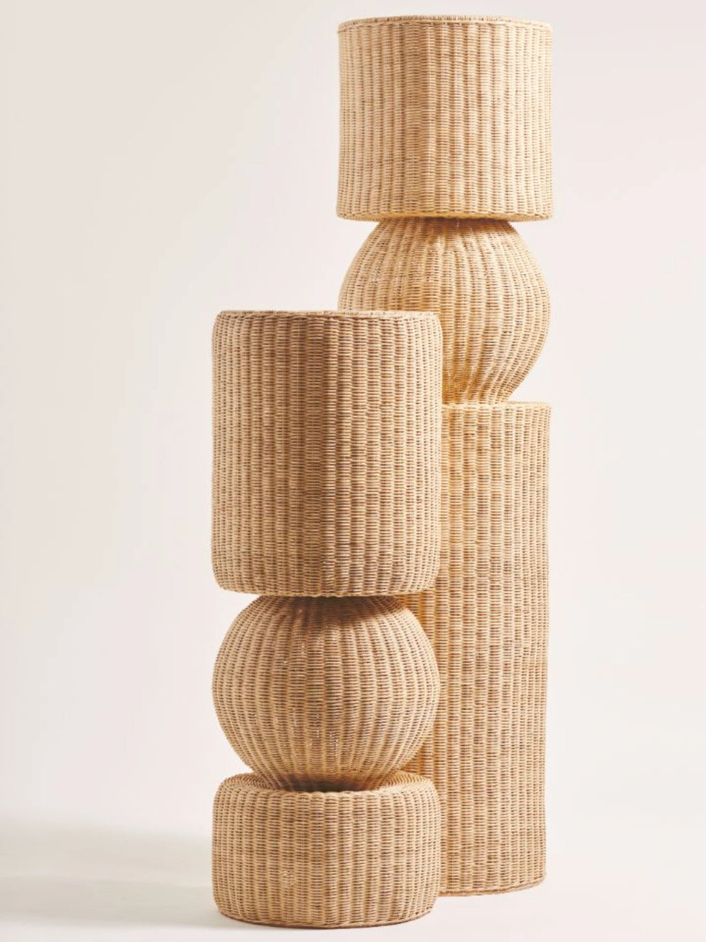 Heaps & Woods Luz Standing Lamp, a tall, sculptural standing lamp crafted from natural woven rattan in a light blonde finish. It features stacked cylindrical and spherical sections with a distinctive ribbed texture, creating an organic modern silhouette. Ideal as a statement floor lamp for contemporary living rooms, coastal-inspired bedrooms, or minimalist entryways.