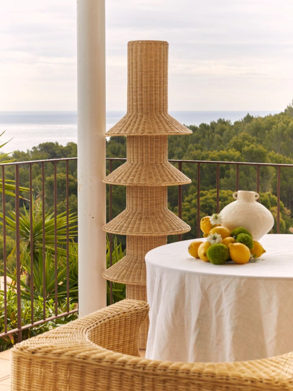 Heaps & Woods Rose Floor Lamp, a tall, sculptural floor lamp handcrafted from natural woven rattan in a light tan finish, featuring a distinctive tiered design with multiple flared conical shades stacked vertically. This organic modern rattan lamp provides a warm, diffused glow, perfect for creating a relaxed coastal or bohemian ambiance in living rooms, bedrooms, or covered outdoor spaces.