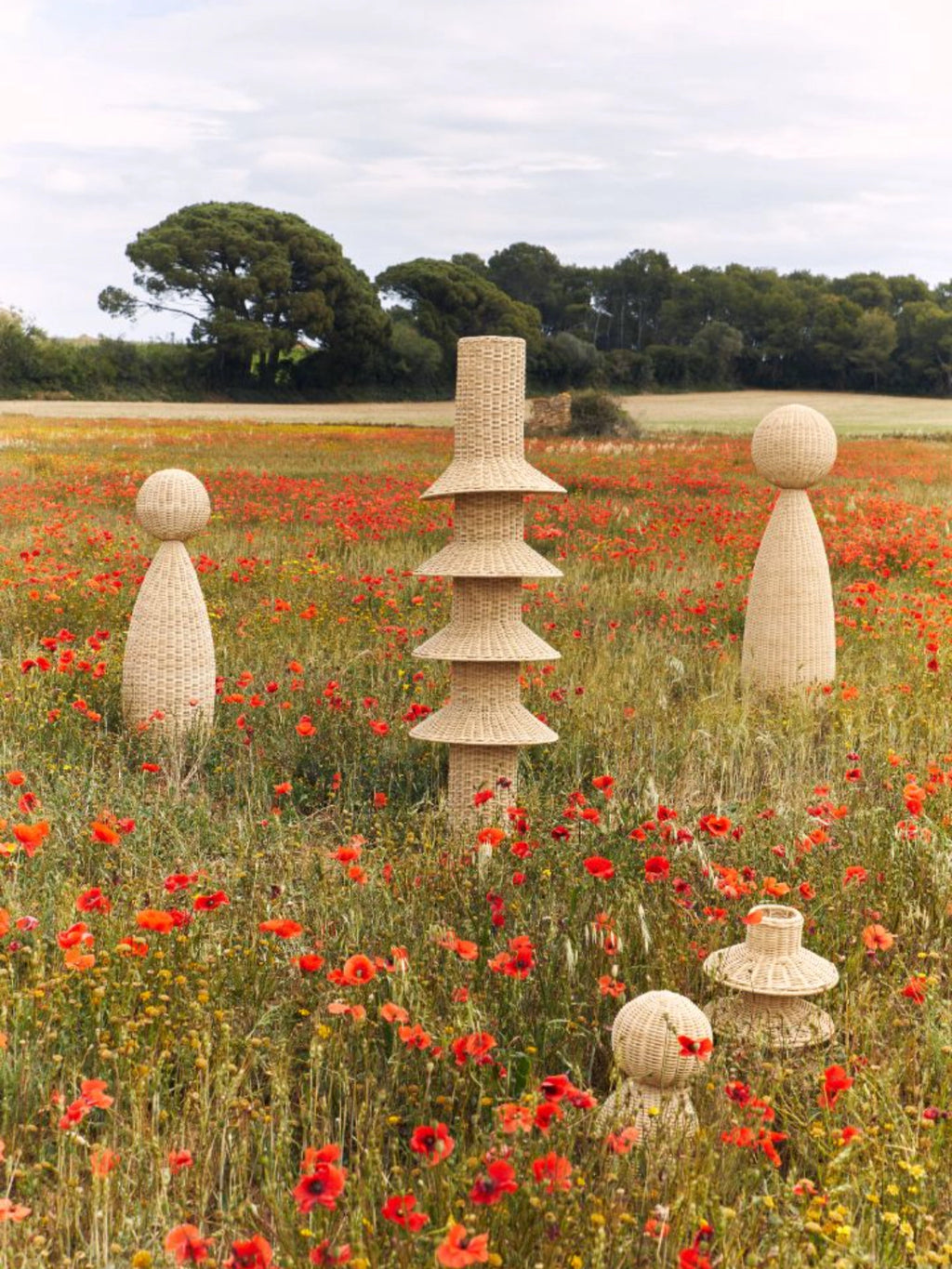 Heaps & Woods Rose Floor Lamp, a tall, sculptural organic modern floor lamp meticulously crafted from natural hand-woven rattan in a warm light beige. This unique lighting fixture features a distinctive tiered design with stacked conical and cylindrical forms, showcasing a beautiful woven texture. Ideal as a statement piece or accent lighting for bohemian, coastal, or contemporary living rooms and bedrooms.