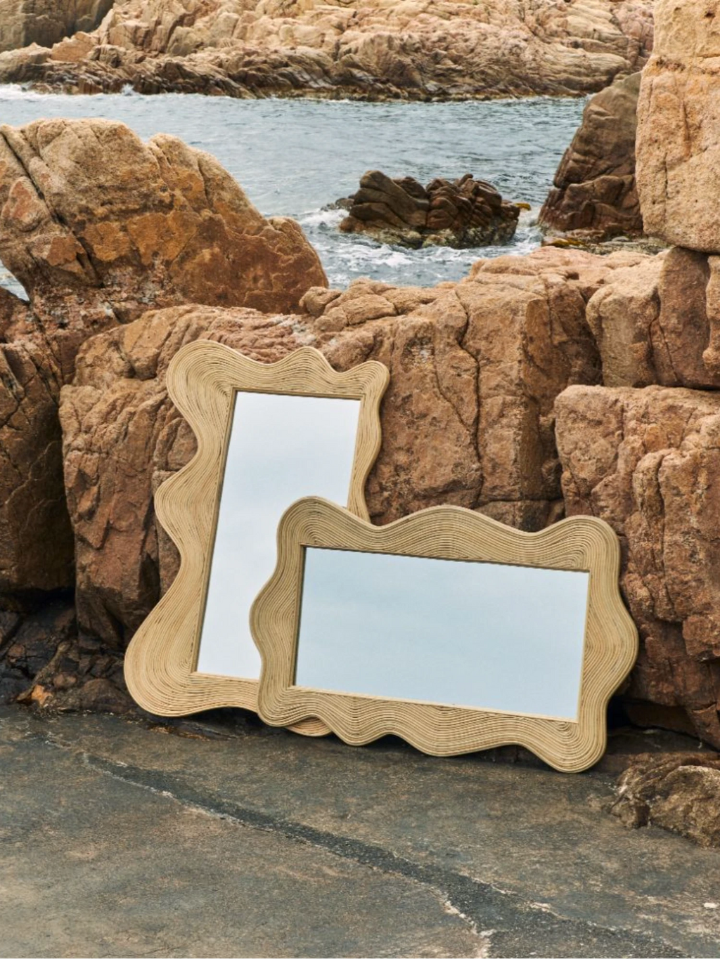 Heaps & Woods Sofia Mirror, an organic modern mirror featuring a distinctive wavy, free-form silhouette with a frame crafted from natural blonde rattan.