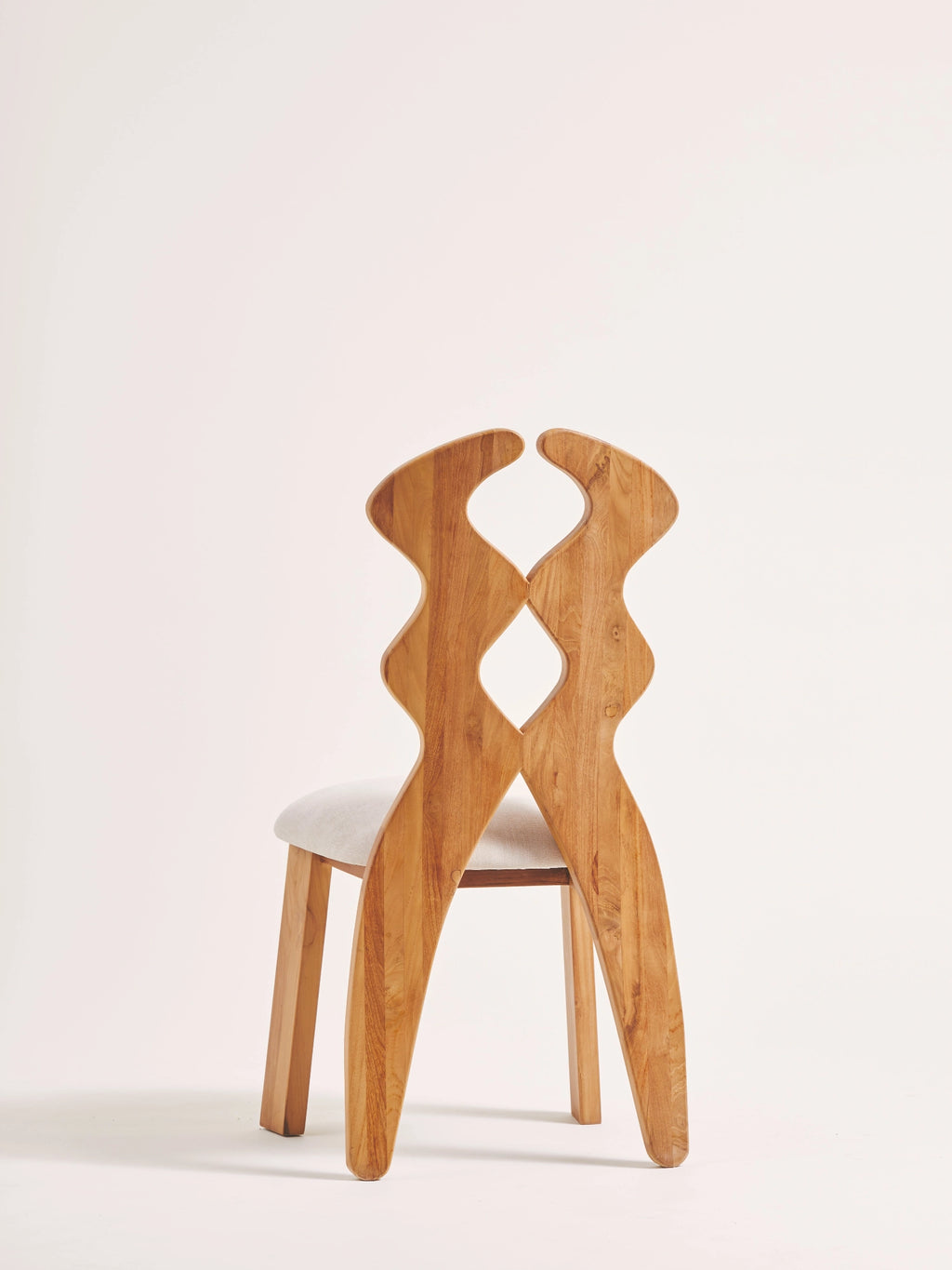 Heaps & Woods Curvy Dining Chair, a sculptural organic modern dining chair crafted from warm natural solid wood featuring a distinctive wavy, interlocking backrest with a central diamond-shaped cutout and a soft.