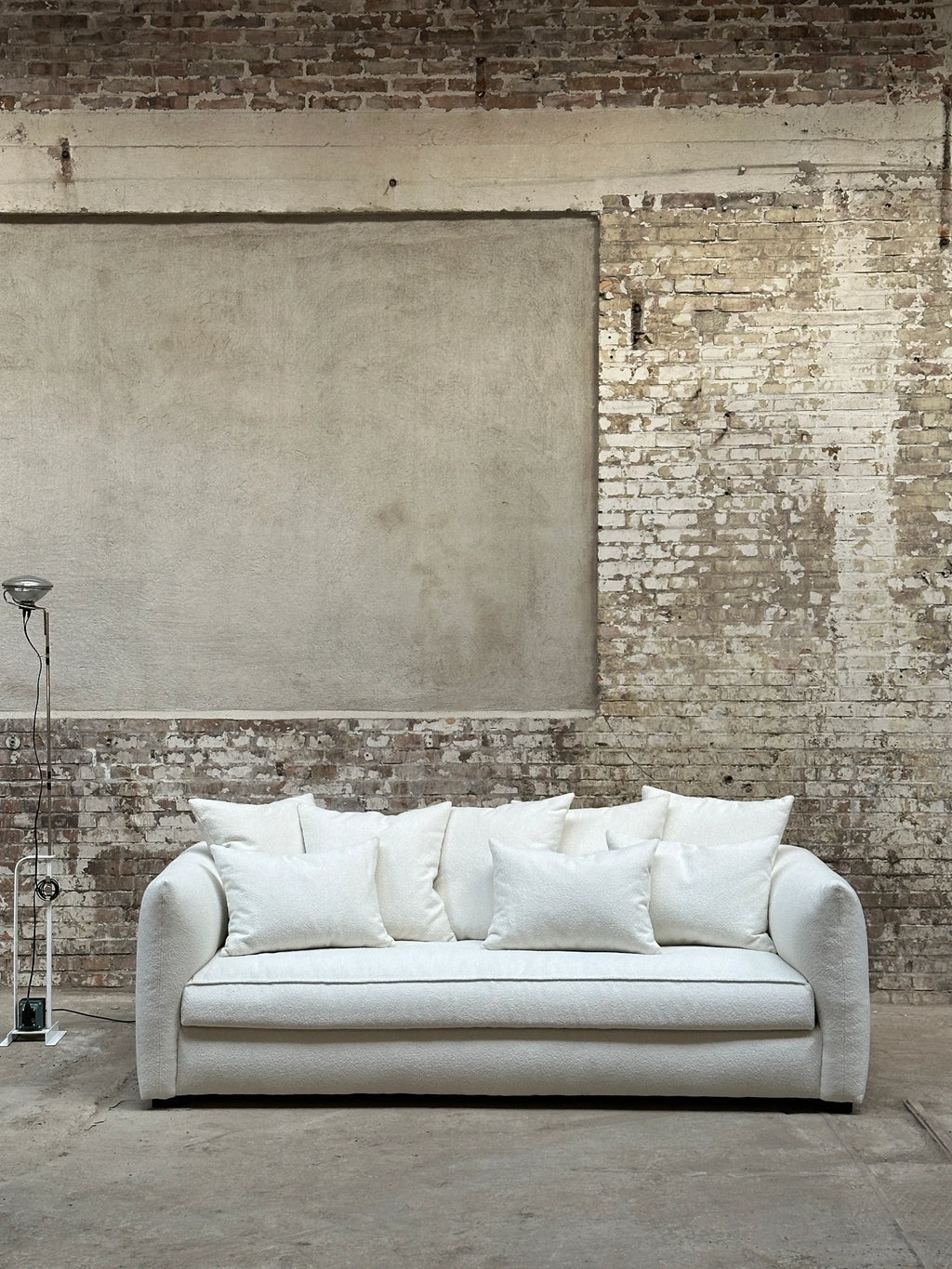 Tinted Objects Cornell Sofa, a luxurious off-white textured fabric sofa with plush back cushions and a sleek, modern design. This elegant living room centerpiece is perfect for contemporary homes seeking comfort and sophisticated style.