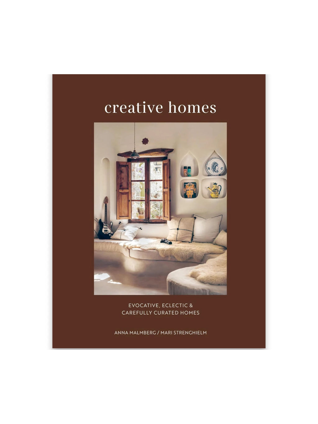 Book Creative Homes, a brown hardcover book featuring an image of an inviting, eclectic living space with a built-in sofa, sheepskin throws, and a wooden-shuttered window. This inspiring interior design book is perfect for homeowners and design enthusiasts seeking unique home decor ideas.