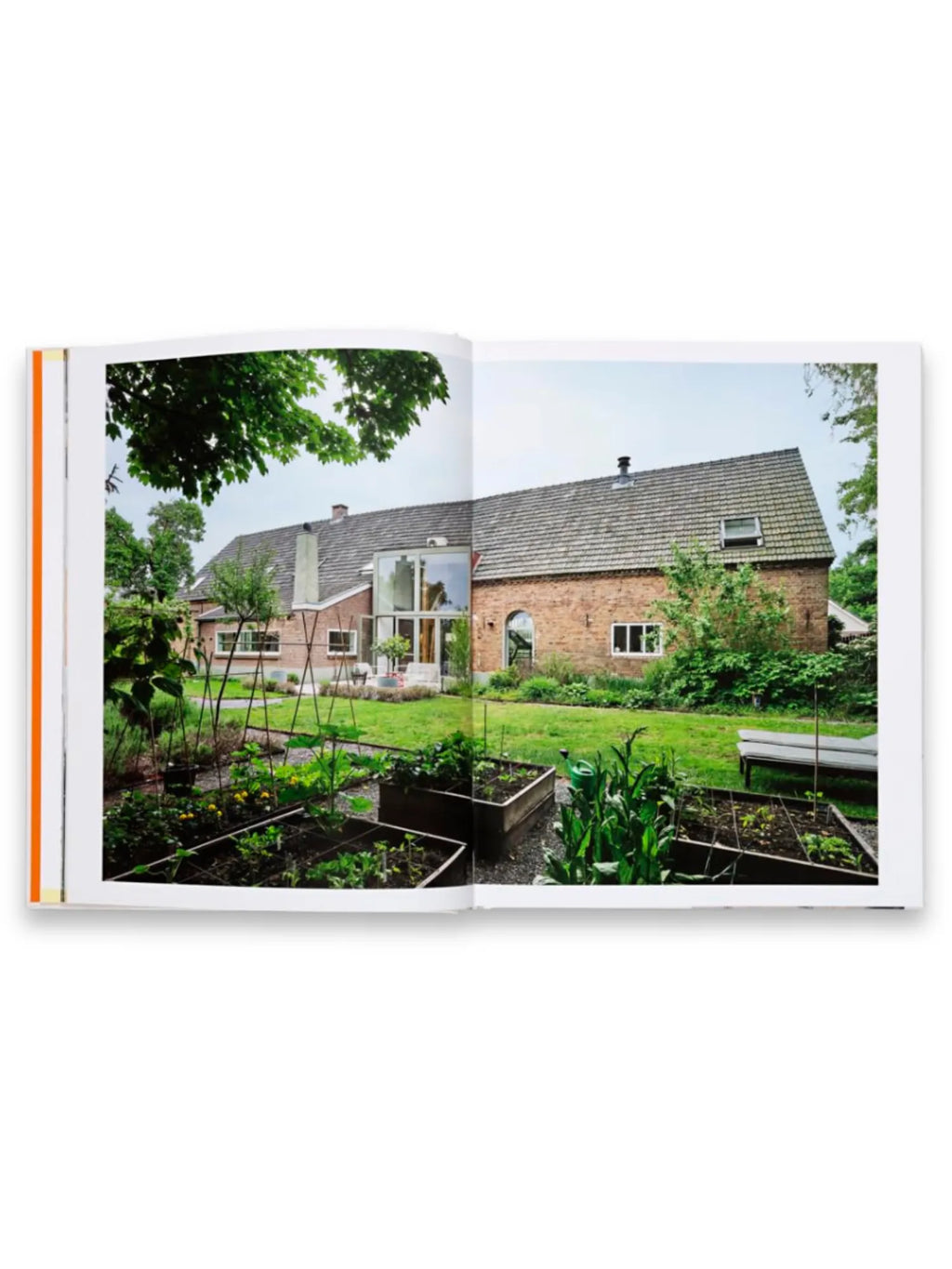 Book, Creative Homes Netherlands, showcasing a rustic brick house with a modern glass extension and a lush green backyard with raised garden beds. This inspiring architectural book is perfect for interior design enthusiasts and homeowners seeking innovative living spaces.