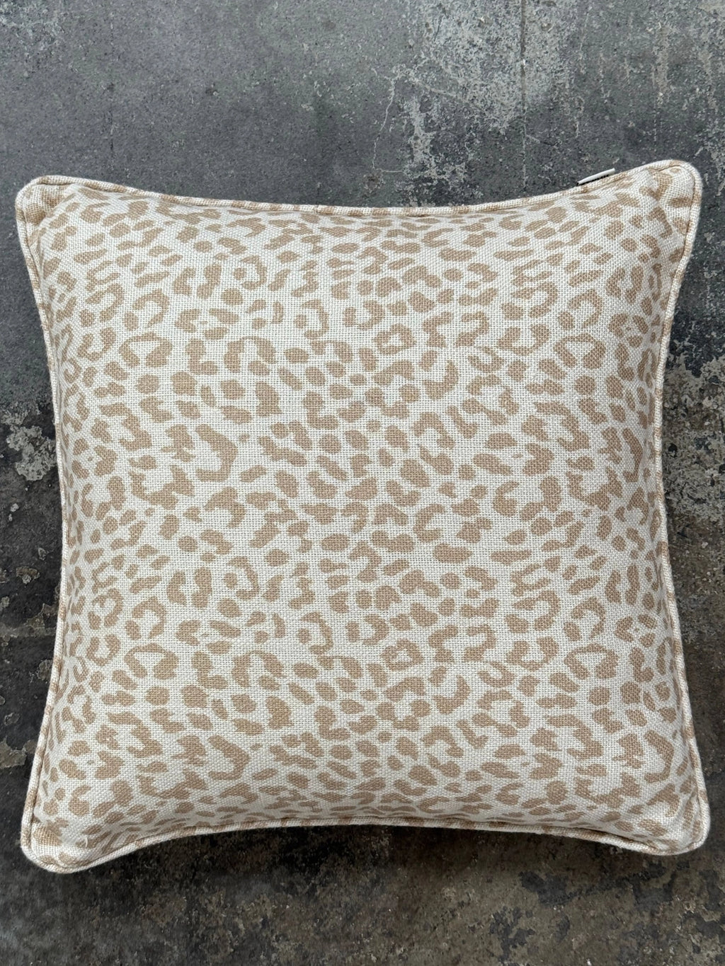 Tinted Objects Norell Throw Pillow, a stylish square cushion featuring a light tan and cream-colored leopard print with a visible woven texture. This decorative accent pillow is perfect for adding a touch of modern wild elegance to any living room sofa, armchair, or bedroom.