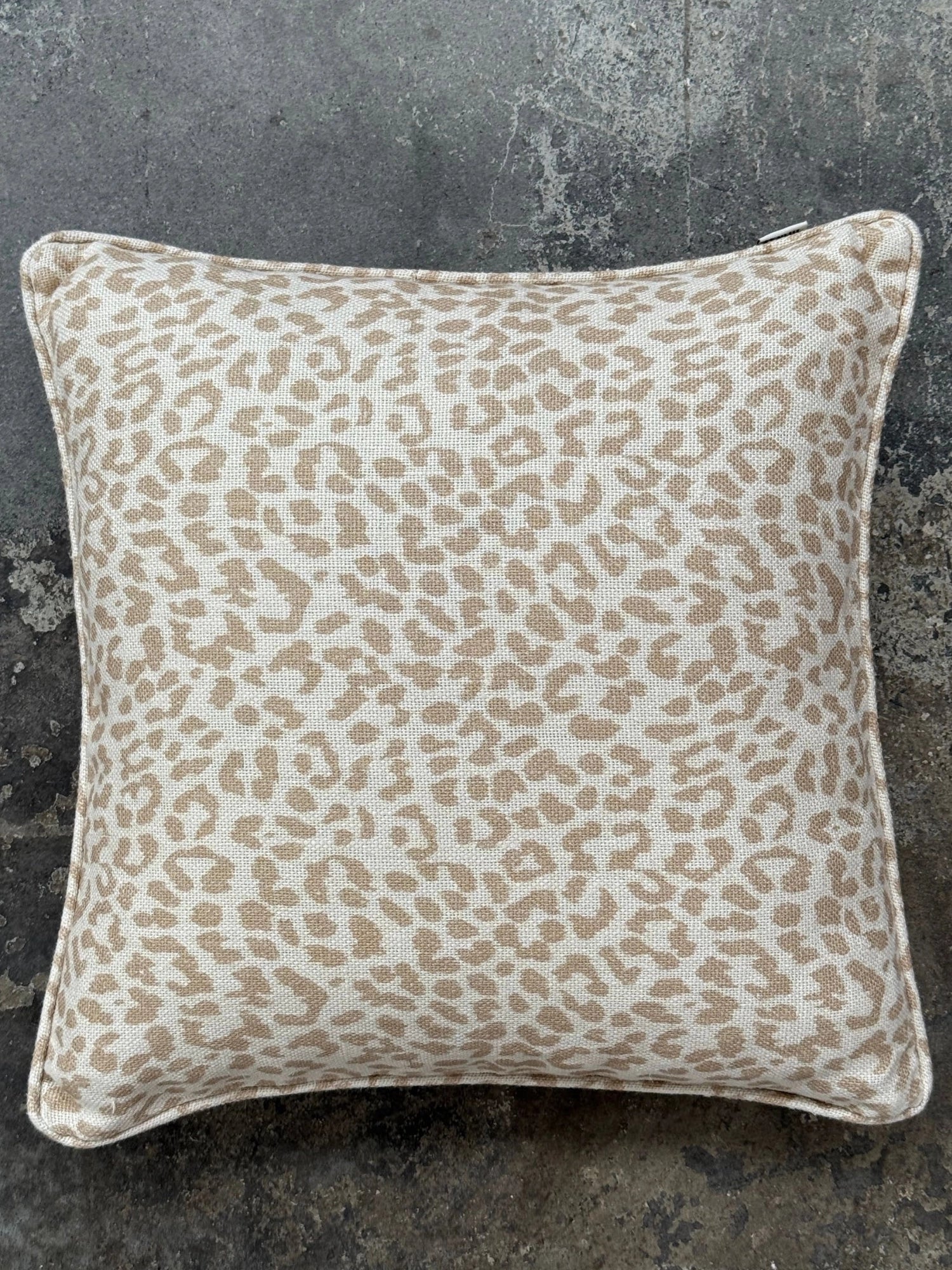 Tinted Objects Norell Throw Pillow, a stylish square cushion featuring a light tan and cream-colored leopard print with a visible woven texture. This decorative accent pillow is perfect for adding a touch of modern wild elegance to any living room sofa, armchair, or bedroom.