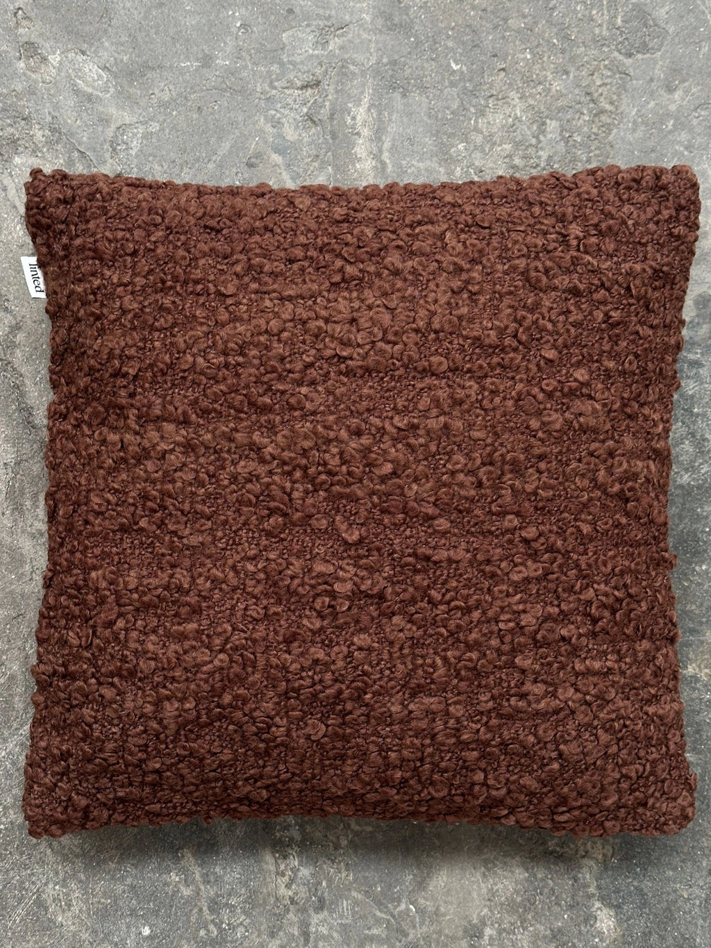 Tinted Objects Levantin Boucle Throw Pillow, a luxurious dark brown boucle cushion with a deeply textured, soft finish. This stylish decorative accent pillow is perfect for adding warmth and comfort to any modern living space or bedroom.