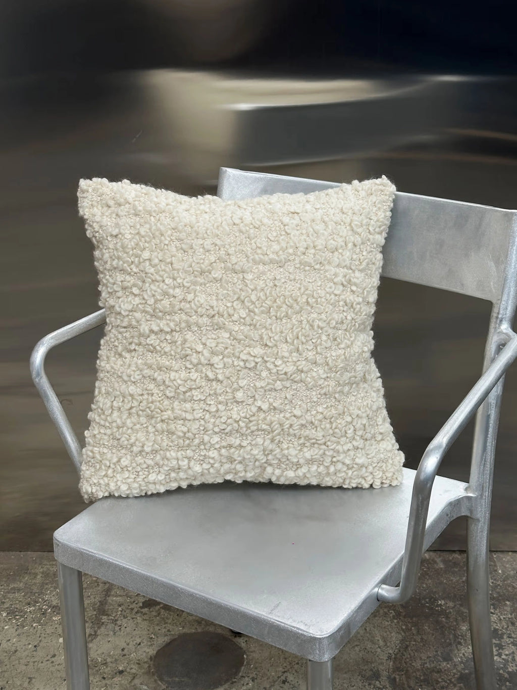 Tinted Objects Levantin Boucle Throw Pillow, a soft cream-colored square cushion with a highly textured, looped boucle fabric. This stylish, cozy accent pillow is perfect for adding warmth and sophisticated texture to modern living spaces for homeowners and interior design enthusiasts.