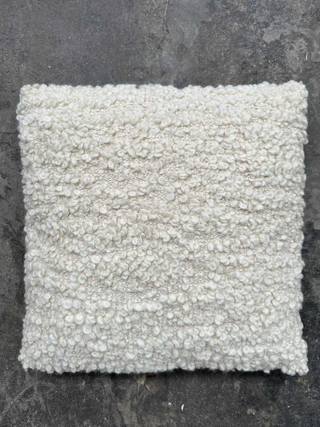 Tinted Objects Levantin Boucle Throw Pillow, a soft, off-white textured cushion with a cozy, looped boucle fabric. This stylish accent pillow is perfect for adding warmth and comfort to modern living spaces for homeowners seeking elegant decor.