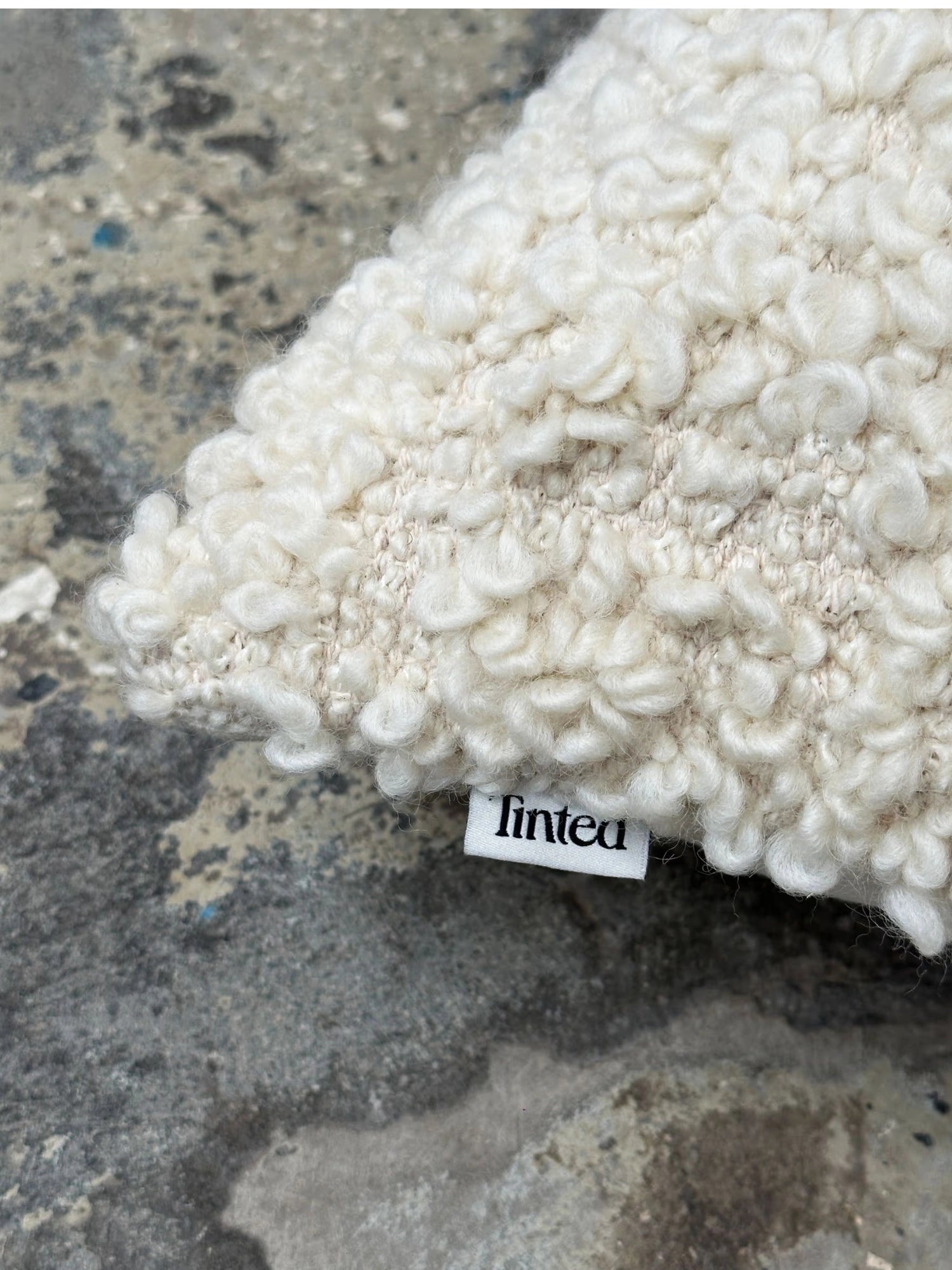 Tinted Objects Levantin Boucle Throw Pillow, featuring a luxurious cream-white boucle texture with visible intricate woven backing and a white "tinted" brand tag. This stylish decorative cushion adds warmth and comfort to any modern living space.