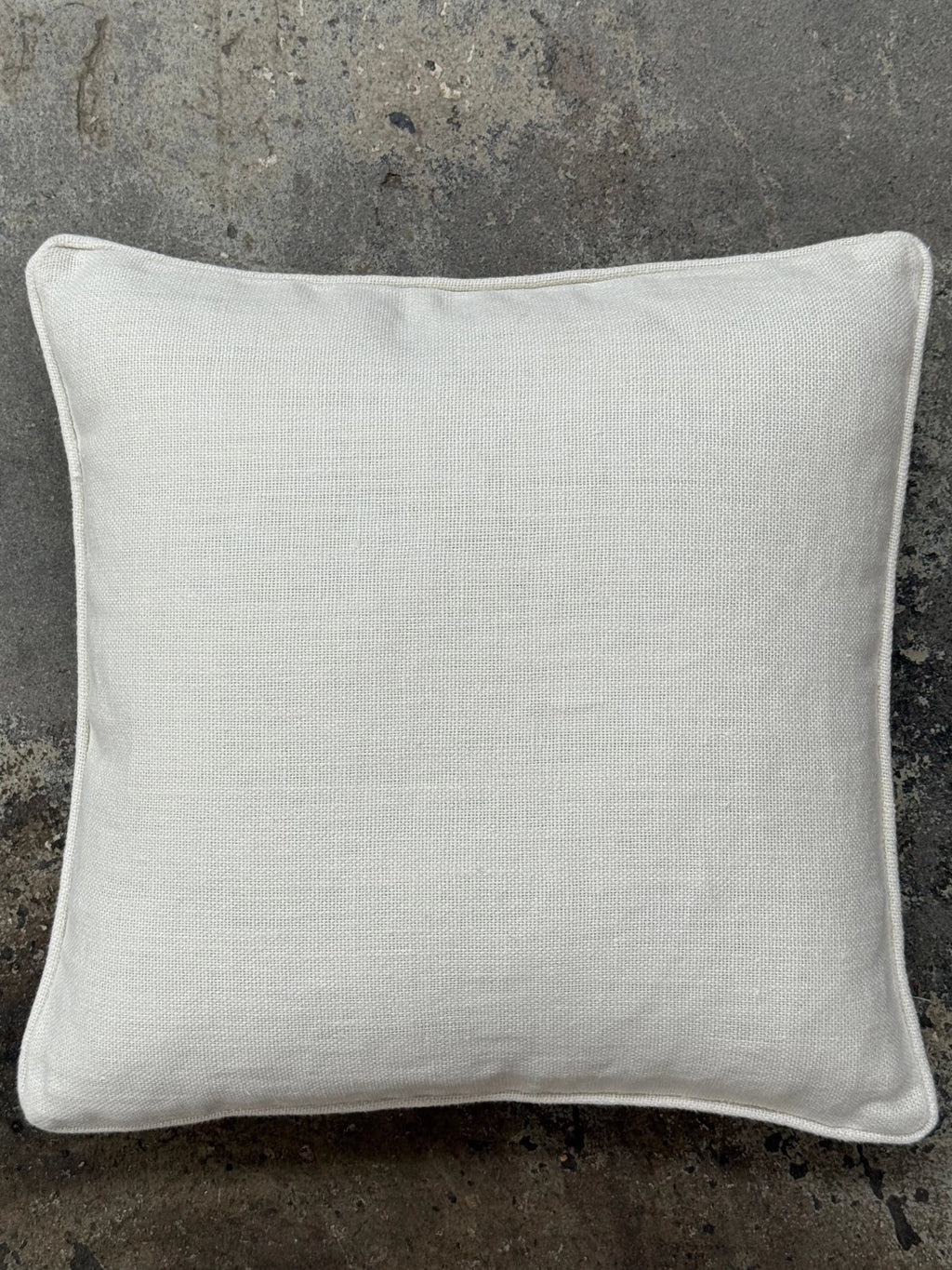 Tinted Objects Norell Throw Pillow, a square white cushion with a durable, textured linen-look fabric and clean piped edges. This versatile accent pillow is perfect for adding comfort and style to any couch, bed, or armchair in a modern or minimalist home.