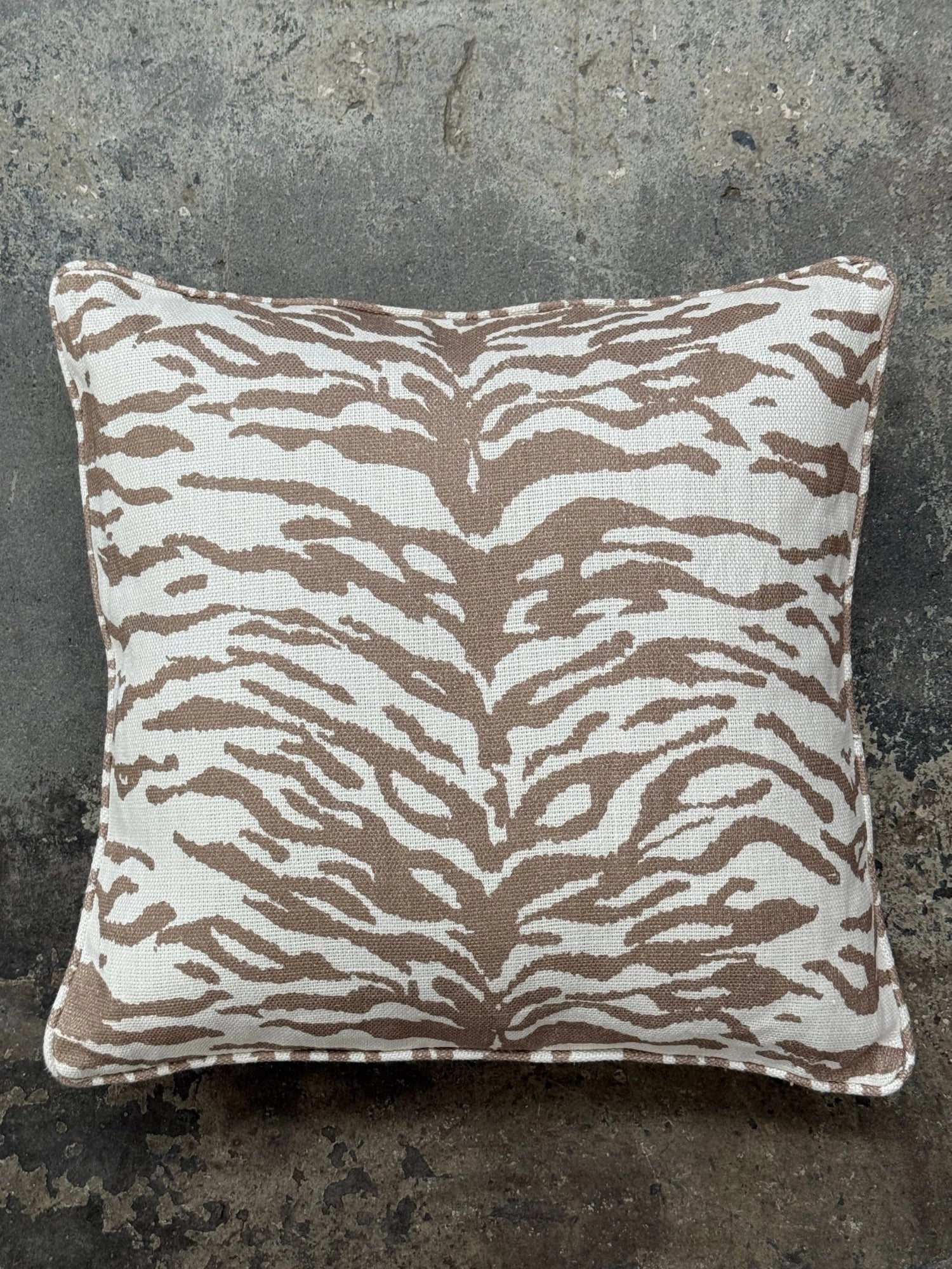 Tinted Objects Norell Throw Pillow, a rectangular decorative cushion featuring a striking taupe and off-white tiger stripe animal print on a textured woven fabric, finished with clean piped edges.