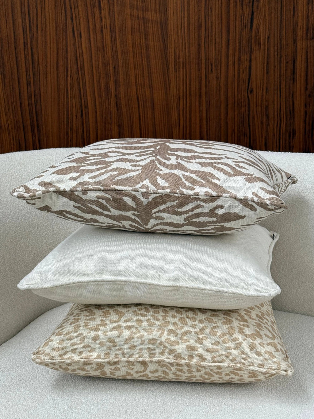 Tinted Objects Norell Throw Pillow, a stacked set of three premium decorative cushions with diverse patterns and textures, including a top zebra print, a middle plain off-white, and a bottom leopard print. These stylish pillows are perfect for adding a cozy and chic touch to any modern living room or bedroom decor.