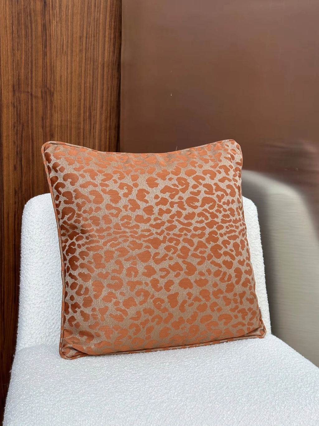 Tinted Objects Vildklint Throw Pillow, a luxurious square cushion featuring a burnt orange and beige leopard print pattern on a soft, textured fabric. This stylish accent pillow is perfect for adding a touch of modern elegance and comfort to any living room or bedroom decor.