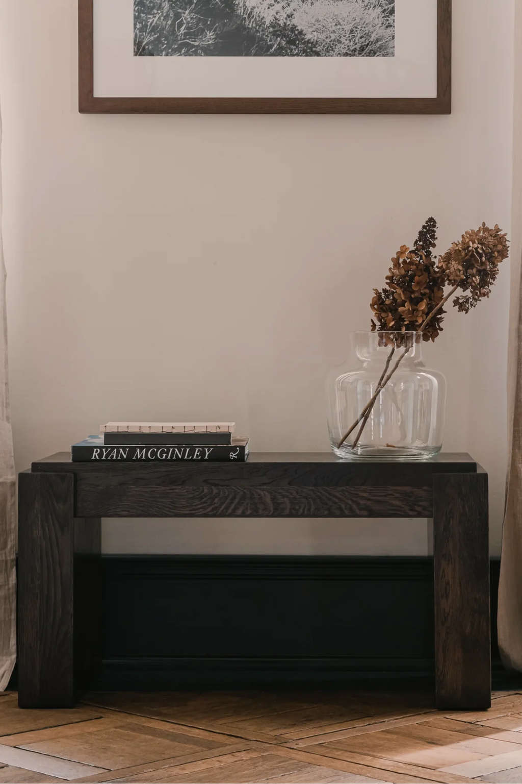 TAMO Pura 80 Bench with thick dark brown wooden top and legs, showcasing rich grain texture in a lifestyle shot with books & vase. A premium, modern entryway bench.