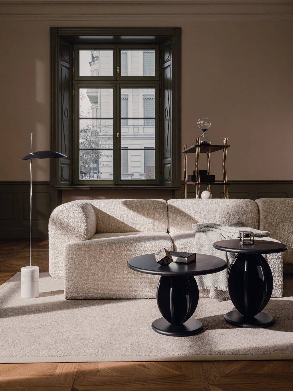 TAMO Citrus Coffee Table duo, featuring two premium matte black tables with rounded tops and distinctive carved orb-shaped bases, styled on a beige rug. Perfect for stylish living spaces.