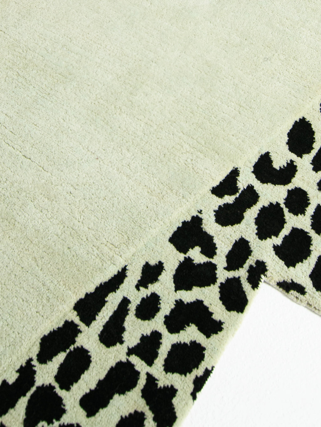 Haus Üger Wild Mist Rug, a contemporary area rug featuring a pale sage green plush pile base with a bold black leopard print pattern, offering a soft tufted texture. Ideal as a statement rug for modern living rooms, contemporary bedrooms, or eclectic home offices.