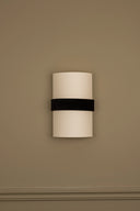 Wall-mounted light fixture with a black band on a beige wall
