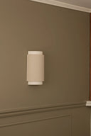 Wall-mounted light fixture on a beige wall with wooden trim
