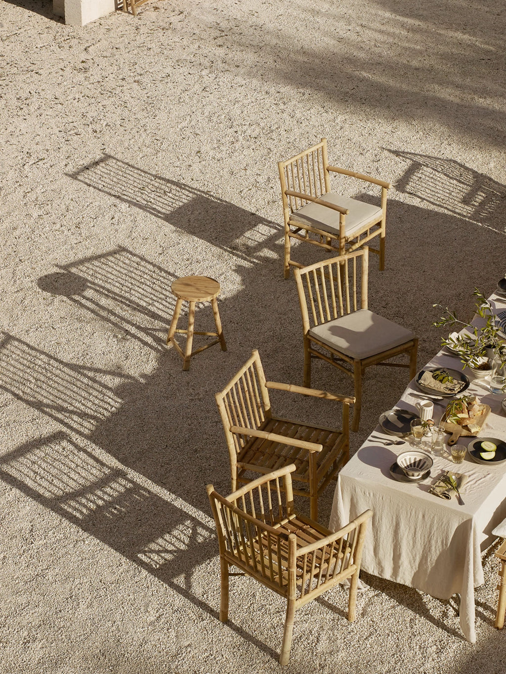 Tine K Outdoor Bamboo Dining Chair With Armrest - Set of 4, featuring a light natural bamboo frame with a slatted backrest, comfortable armrests, and soft beige seat cushions. This organic modern outdoor dining chair set offers a coastal aesthetic for stylish patio, garden, or terrace entertaining.