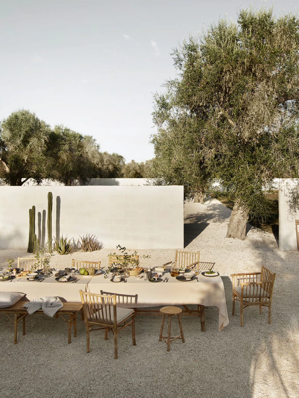 Tine K Outdoor Bamboo Dining Chair With Armrest - Set of 4, a set of four natural bamboo dining chairs, each featuring a sturdy slatted backrest and armrests, paired with soft light cream cushions for comfort. These organic modern patio chairs showcase a rustic, natural material aesthetic with clean lines and a warm, inviting feel. Perfect for creating a relaxed outdoor dining experience in a Mediterranean garden, coastal patio, or boho-chic backyard.