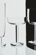 Three clear glassware items on a reflective surface with a black background