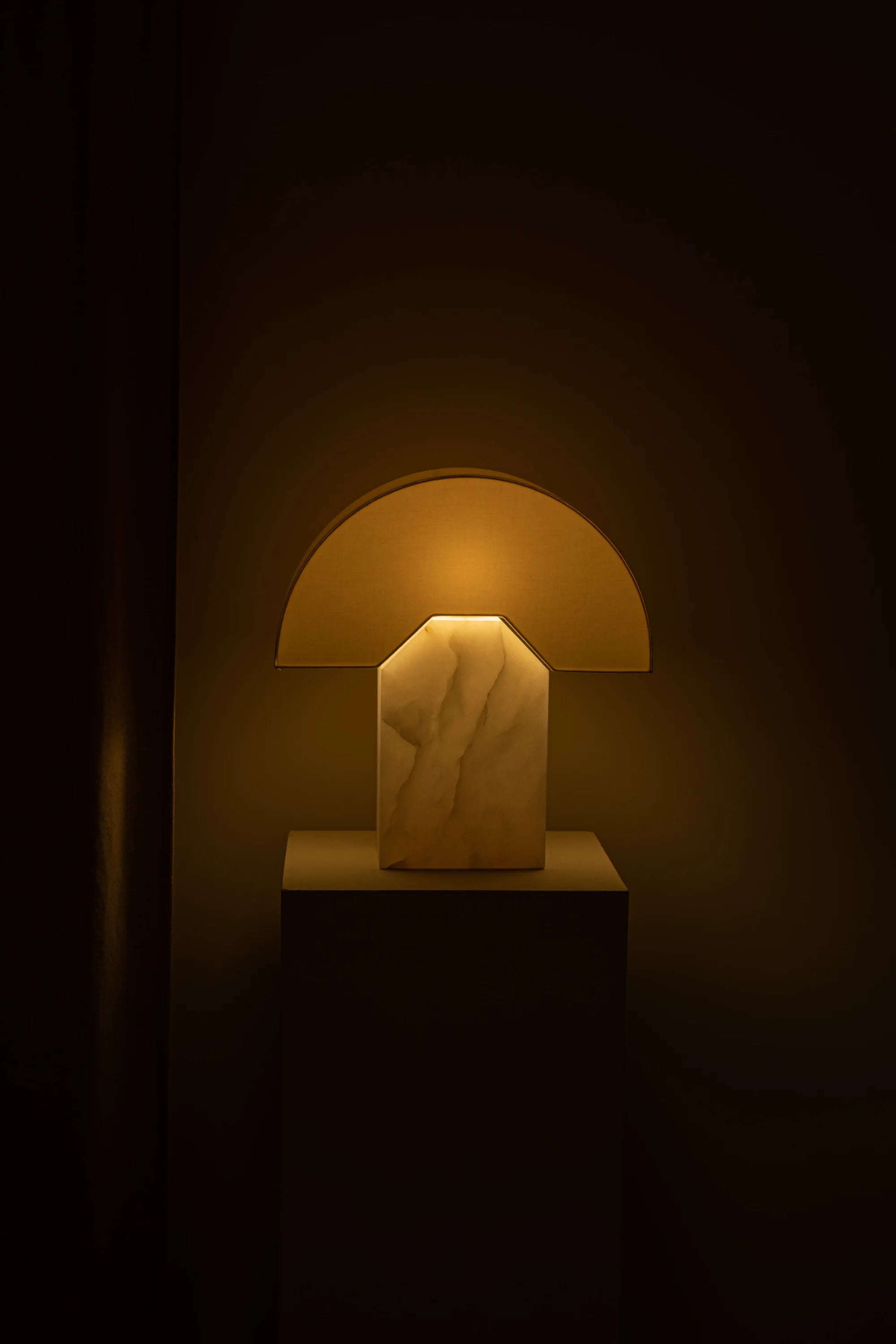 Marble table lamp emitting a warm glow in a dark setting