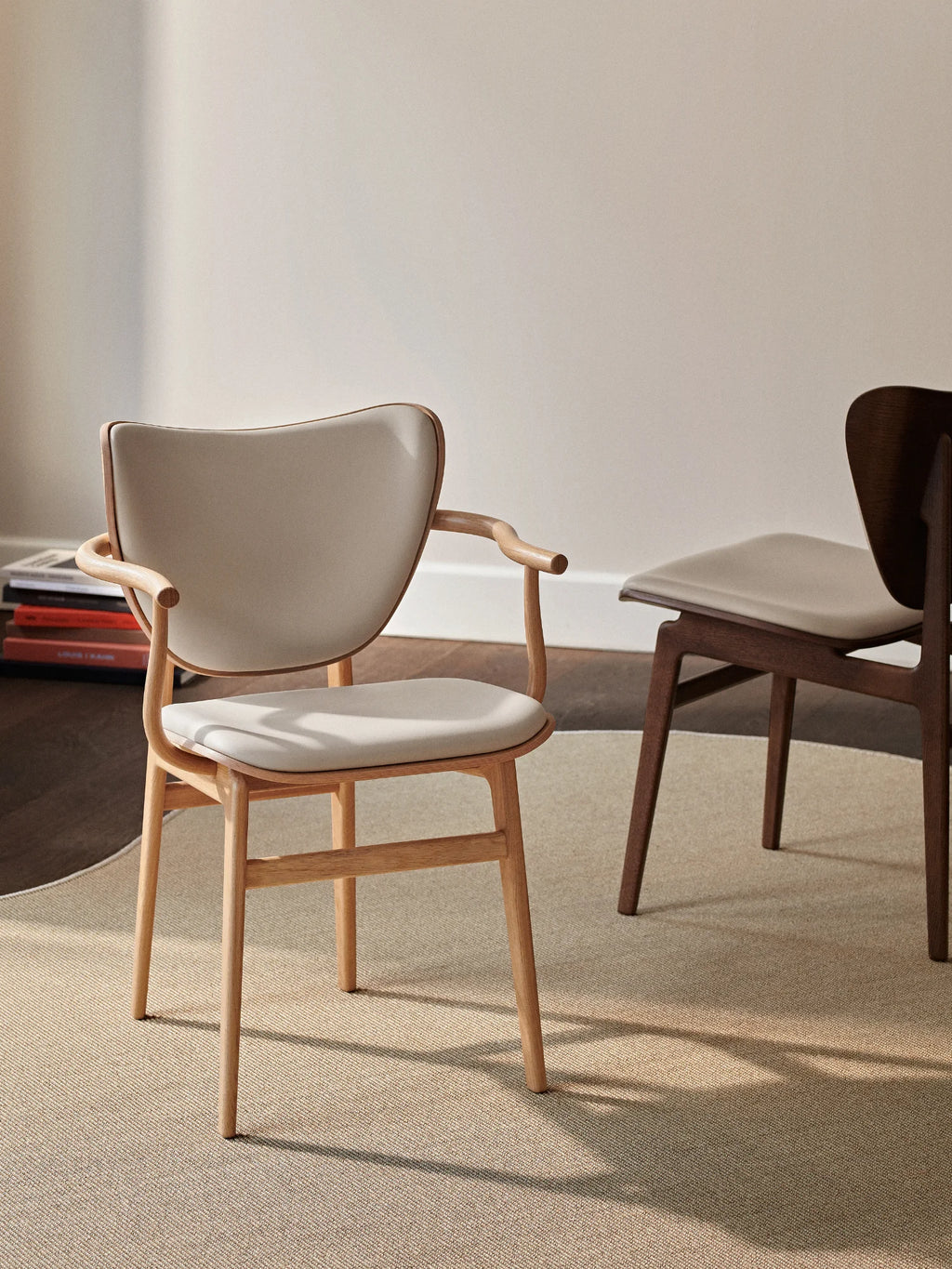 NORR11 Elephant Armchair, a modern and elegant chair crafted with a light wood frame and plush, cream-colored upholstery. Its minimalist design and smooth curves exude a premium feel. This stylish armchair is perfect for adding a touch of sophisticated comfort to any contemporary living space or office.