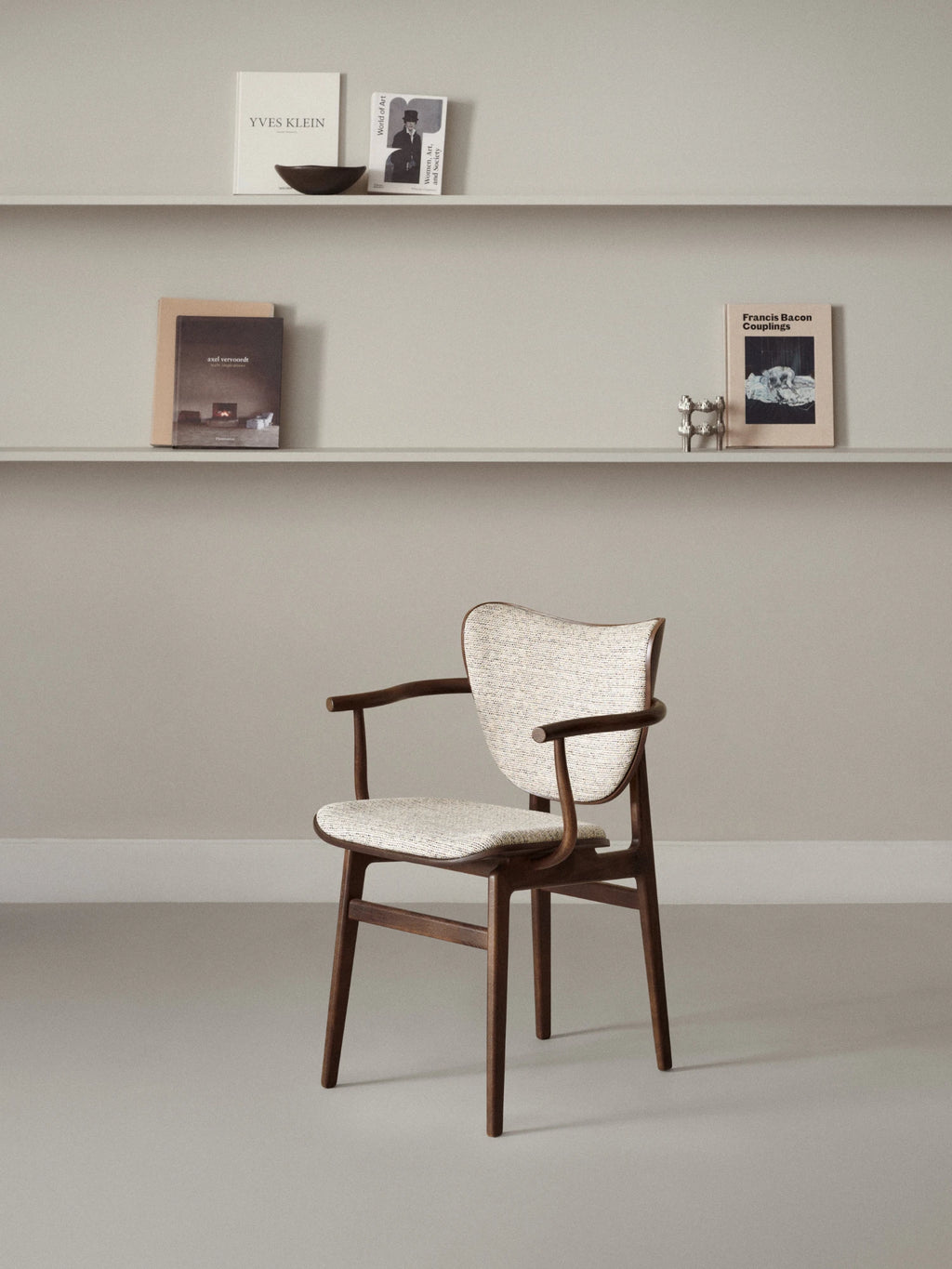 NORR11 Elephant Armchair, a premium modern armchair with a curved backrest & seat upholstered in a textured neutral fabric, supported by a durable, elegant dark wood frame. This stylish chair is perfect for adding a sophisticated touch to any living space or reading nook.