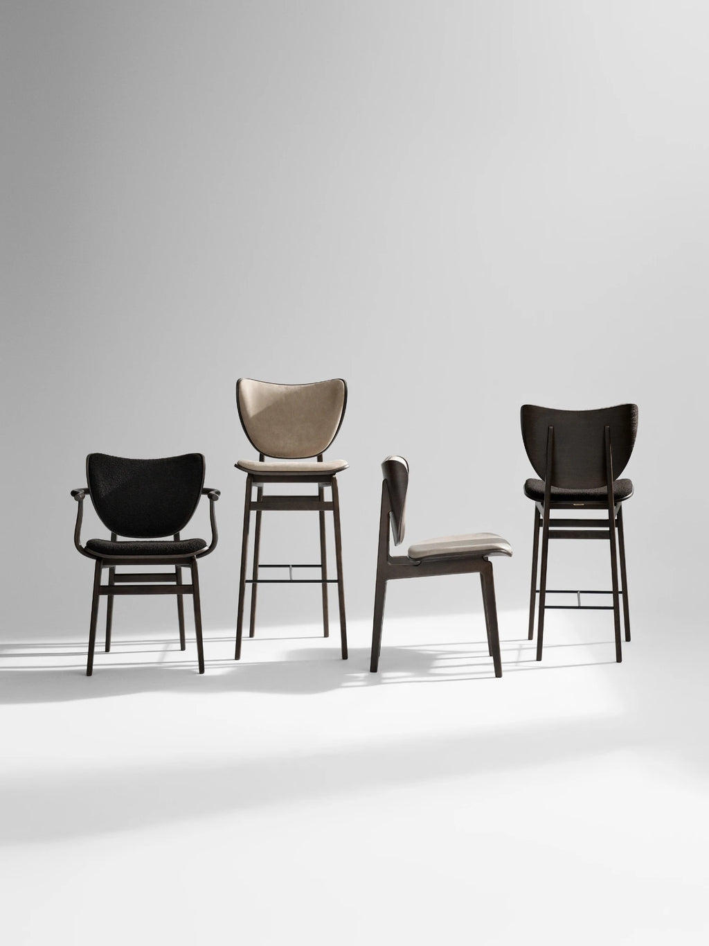 NORR11 Elephant Armchair, Four modern chairs with dark wood frames, one black textured armchair with arms, a light beige upholstered bar stool, and two dark wood dining chairs with textured seats and light beige and dark backrests. Perfect for designers and homeowners seeking stylish, handcrafted seating.