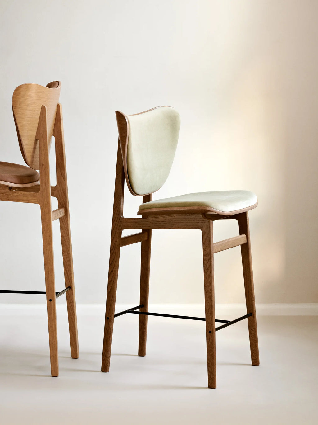 NORR11 Elephant Bar Chair crafted from light oak wood, featuring a light sage green upholstered seat and backrest, displayed indoors. A premium mid-century modern bar stool.