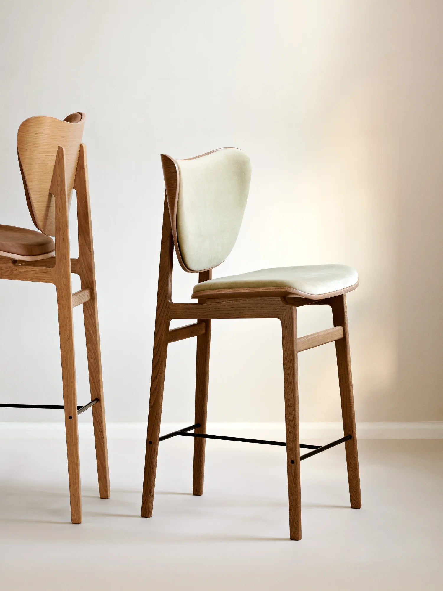 NORR11 Elephant Bar Chair crafted from light oak wood, featuring a light sage green upholstered seat and backrest, displayed indoors. A premium mid-century modern bar stool.