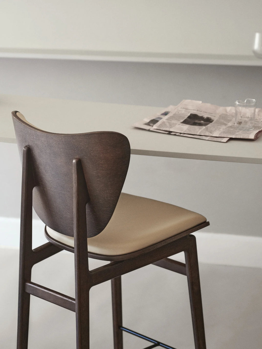 NORR11 Elephant Bar Chair with curved dark walnut wood backrest and legs, paired with a beige leather upholstered seat. This premium bar stool is ideal for kitchen islands or home bars.