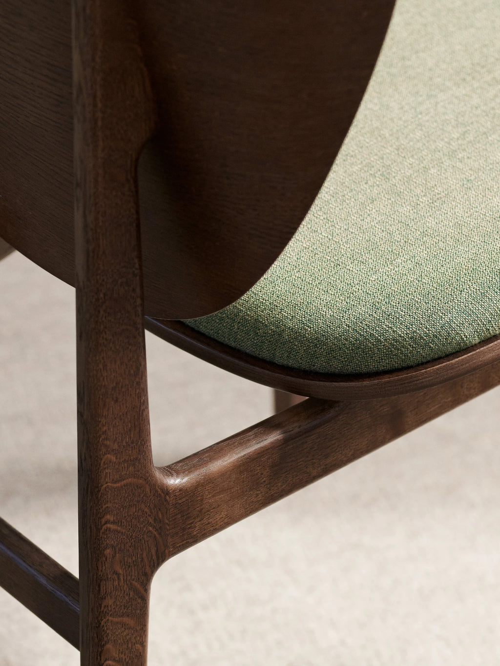 NORR11 Elephant Chair, a mid-century modern dining chair featuring a dark stained solid oak wood frame with beautifully curved, organic lines and a finely woven sage green fabric upholstered seat.