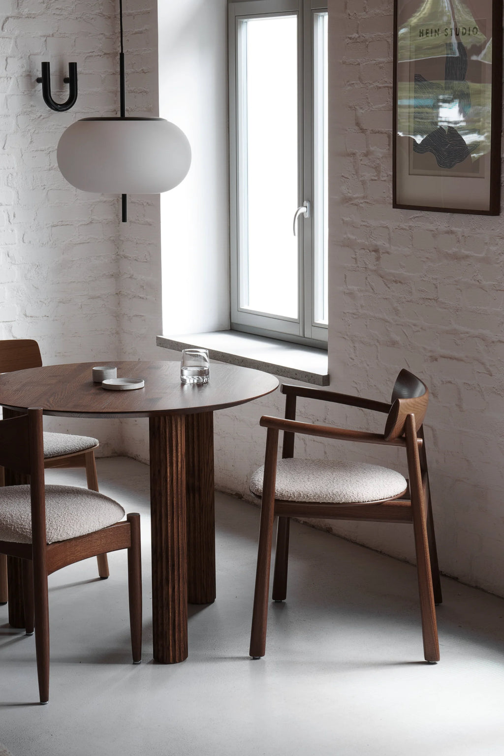 TAMO Elipsa Chair, a luxury dark walnut wood dining chair with curved backrest and light textured boucle fabric seat, shown in a lifestyle dining setting. Perfect for elegant interiors.