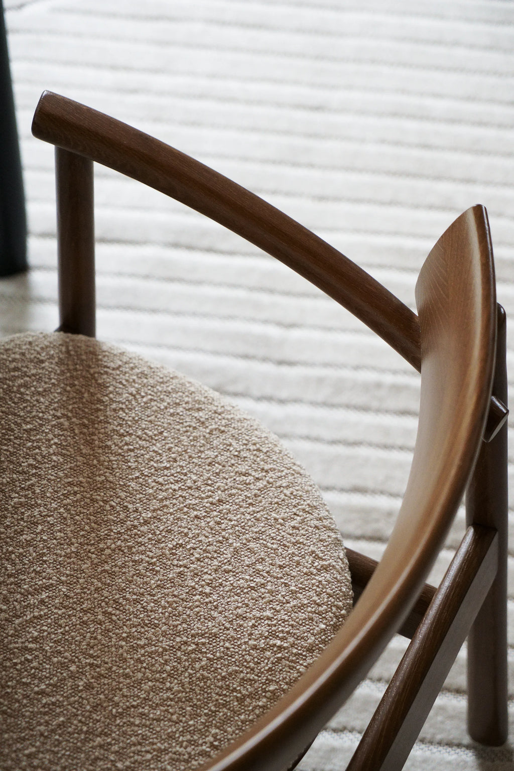TAMO Elipsa Chair, showcasing its premium dark brown wooden frame with a curved backrest and natural light beige boucle upholstered seat on a textured white rug. Ideal for luxurious dining or accent seating.