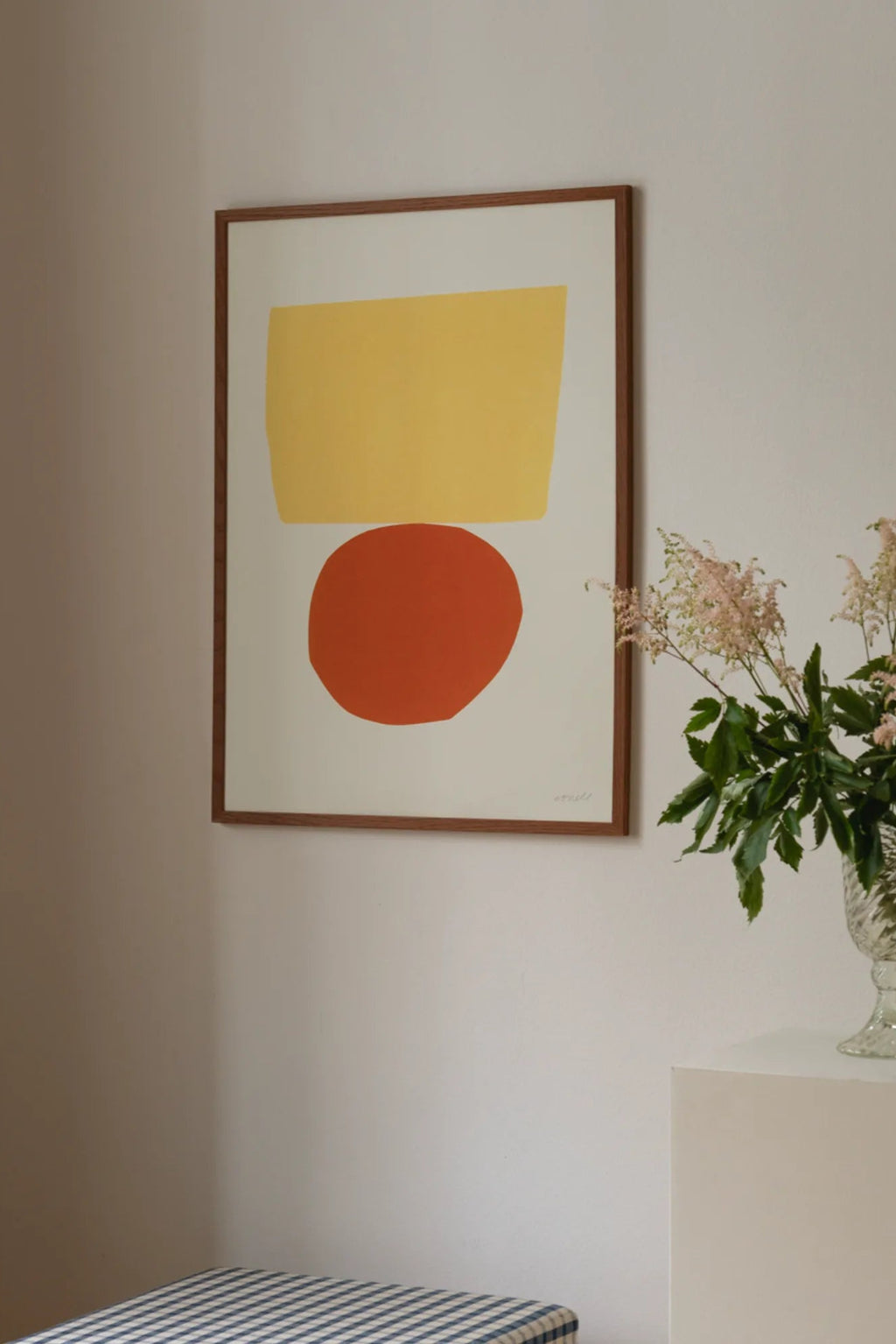 The Poster Club Balancing Act, a modern abstract art print featuring a bold mustard yellow rectangle shape balanced above a vibrant terracotta orange circle on a cream background. This contemporary wall art piece is framed in a sleek dark wood frame, making it ideal for minimalist living rooms, mid-century modern bedrooms, or gallery wall styling.