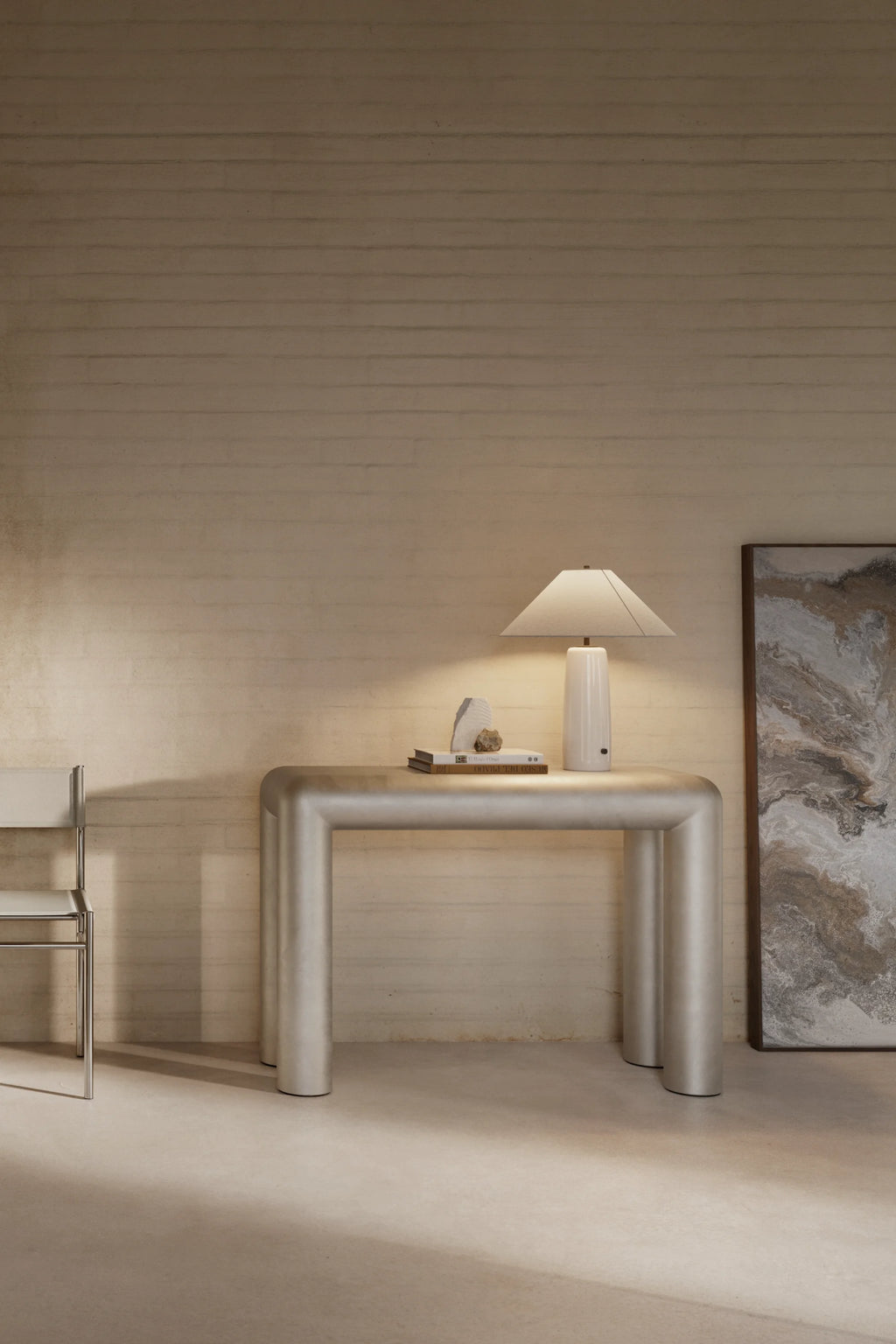 Modern interior with a metallic console table, lamp, and abstract painting against a wooden wall.