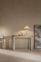 Modern interior with a metallic console table, lamp, and abstract painting against a wooden wall.