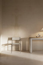 Minimalist chair and table in a softly lit room with wooden walls.