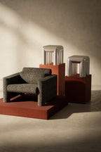 Modern chair and stools on a textured floor with a neutral wall background