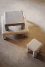 Two white stools on a concrete floor